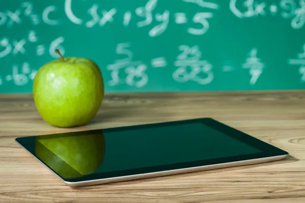 Цифровая таблетка и яблоко на столе — стоковое фото